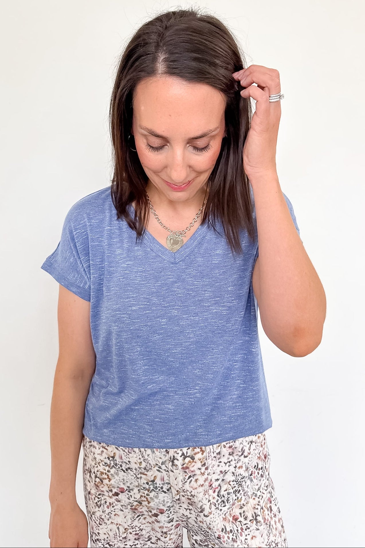 Woman wearing a blue t-shirt and floral pants against a white background