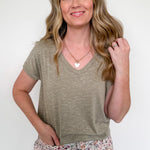 Woman wearing a green t-shirt and floral pants against a white background