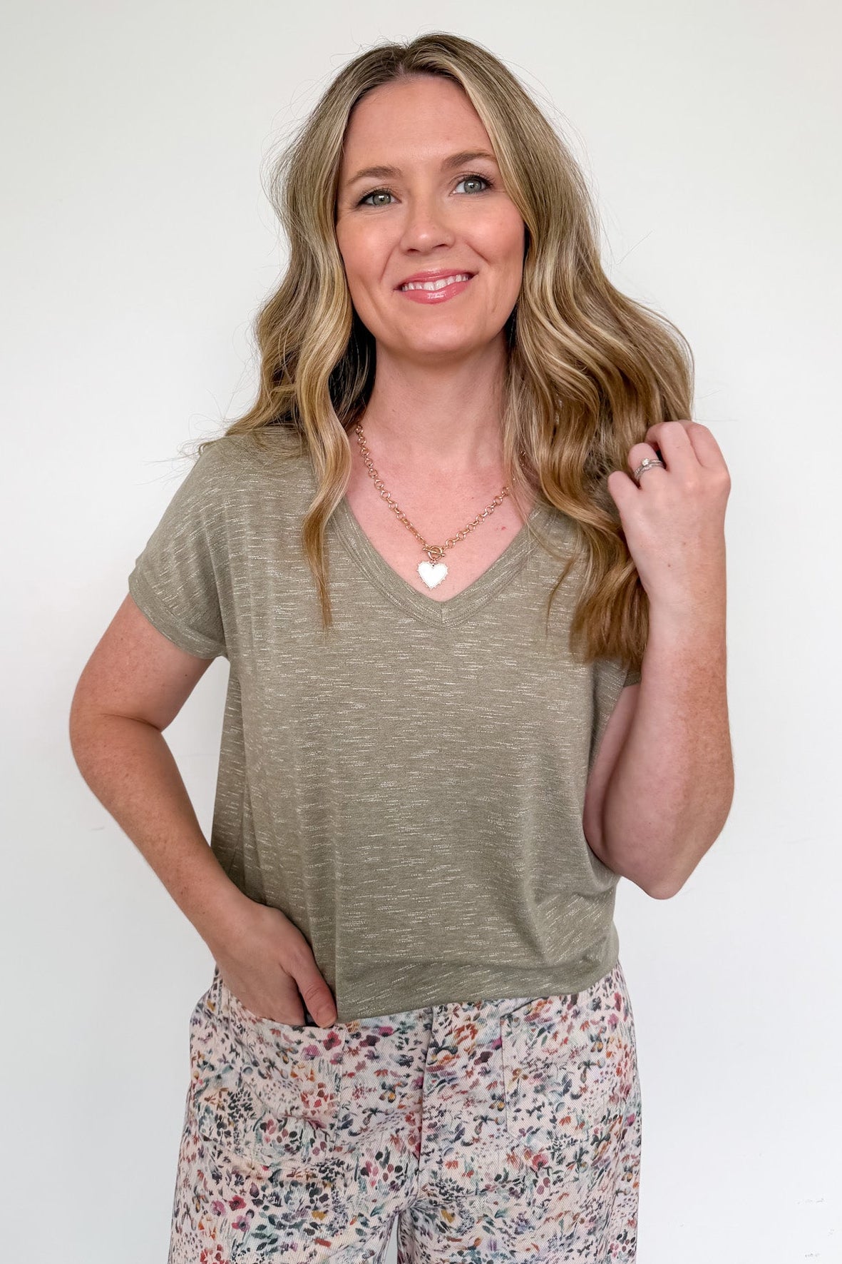 Woman wearing a green t-shirt and floral pants against a white background