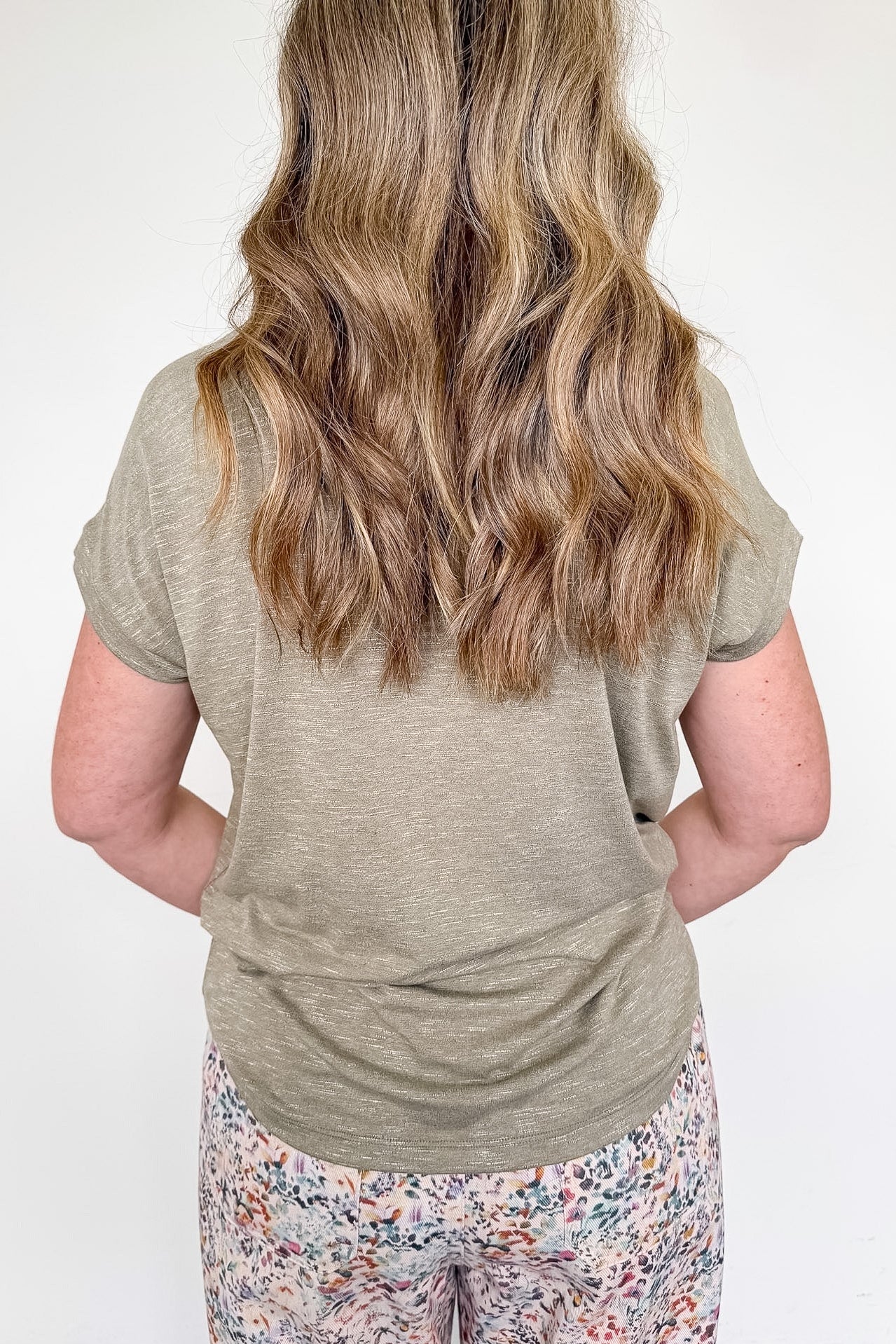 Person wearing a green t-shirt and floral pants against a white background