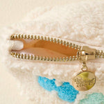 Close-up of a gold zipper on a textured surface with a brand tag.