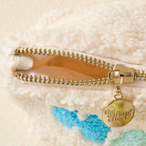 Close-up of a gold zipper on a textured surface with a brand tag.