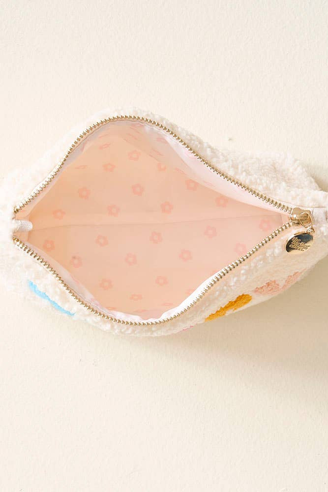 Small pink pouch with gold zipper on a beige background