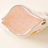Small pink pouch with gold zipper on a beige background