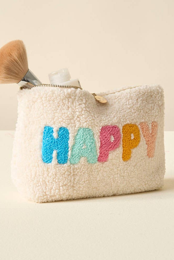 Beige textured pouch with 'HAPPY' in colorful letters, brush, and bottle on a beige background