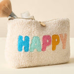 Beige textured pouch with 'HAPPY' in colorful letters, brush, and bottle on a beige background