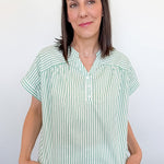 Woman wearing a green and white striped shirt against a plain background