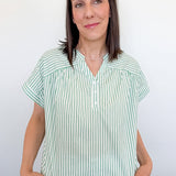 Woman wearing a green and white striped shirt against a plain background