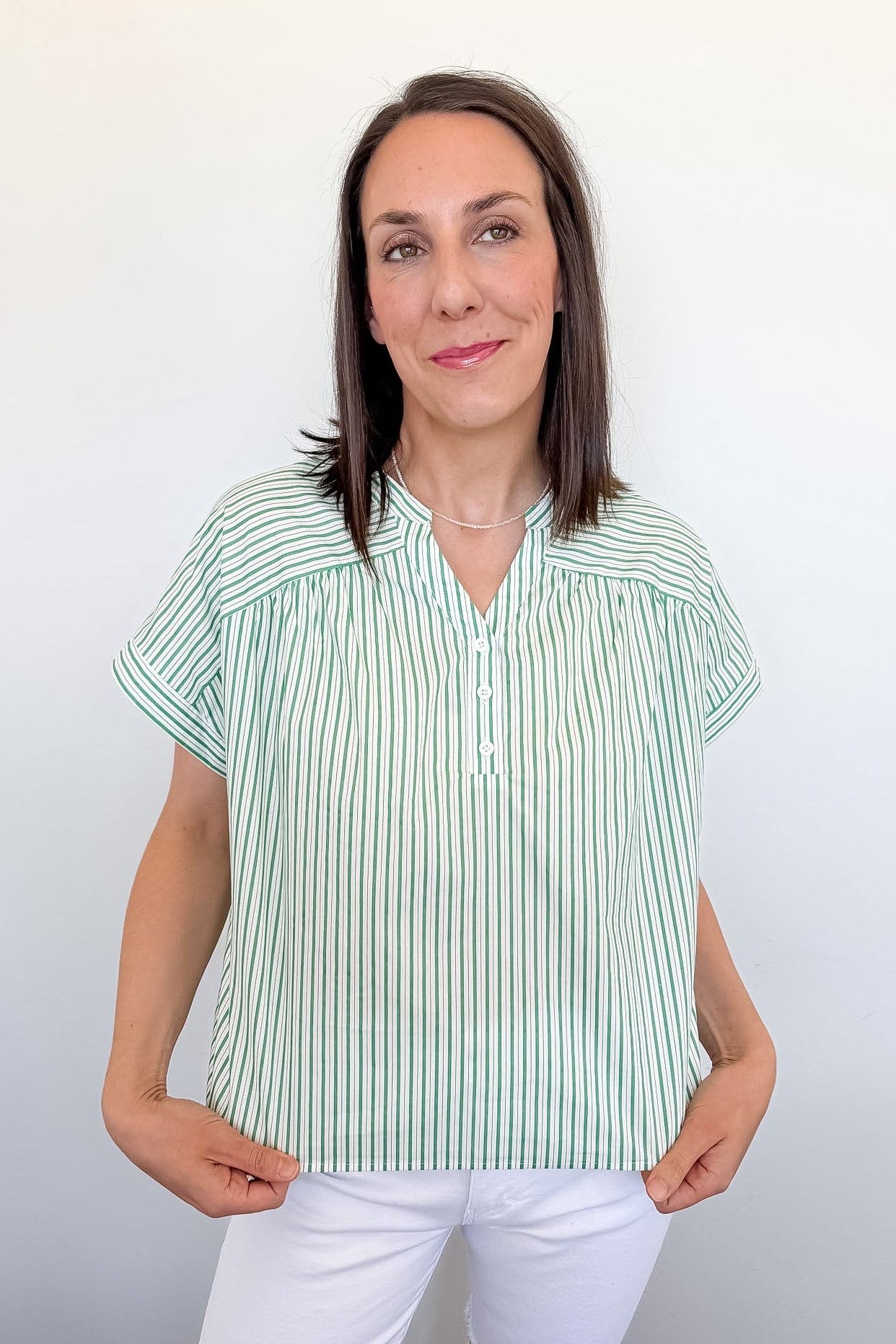 Woman wearing a green and white striped shirt against a plain background