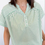 Woman wearing a green and white striped shirt against a plain background