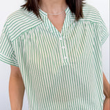 Woman wearing a green and white striped shirt against a plain background