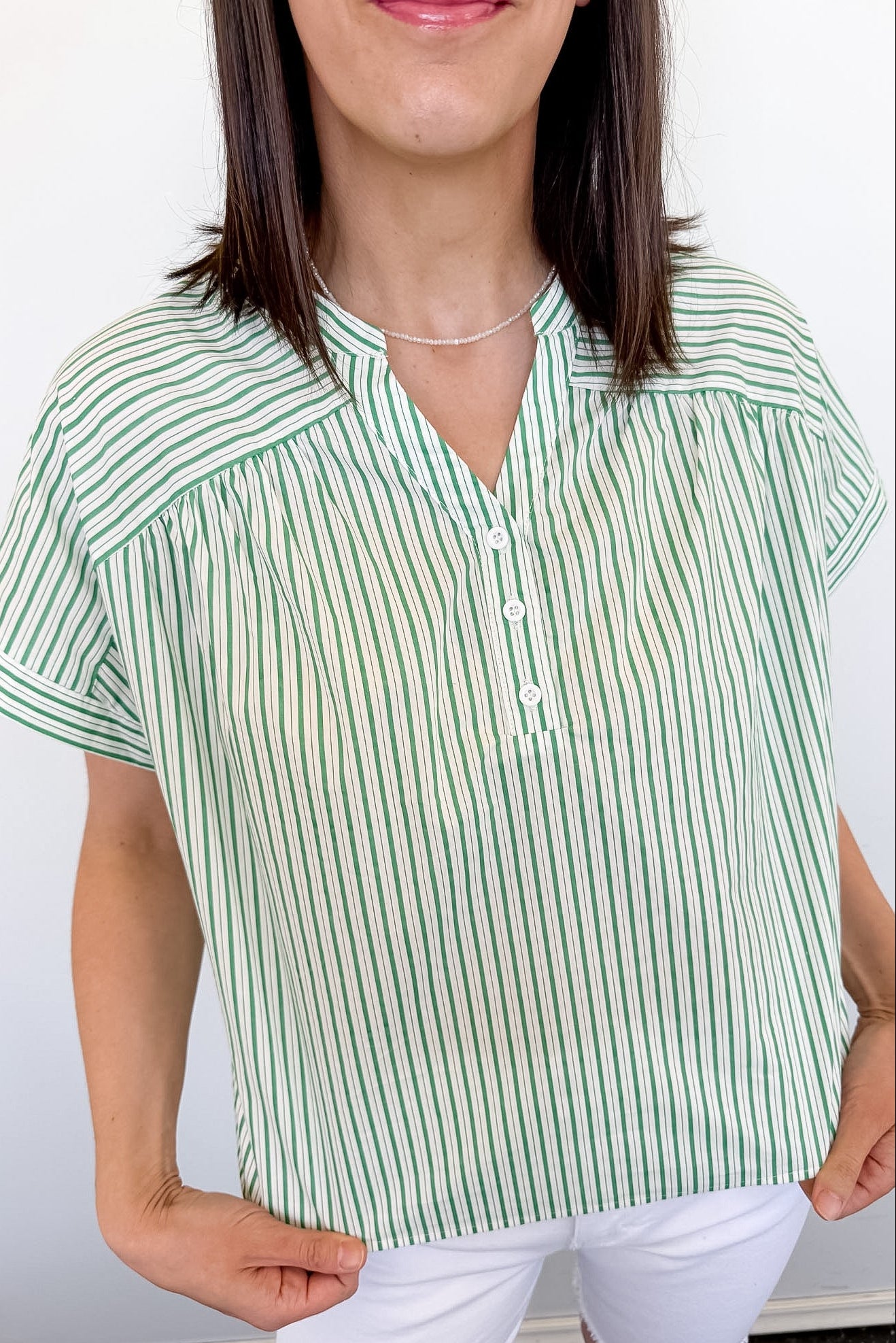 Woman wearing a green and white striped shirt against a plain background