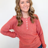 Woman wearing a red long-sleeve shirt and blue jeans against a white background