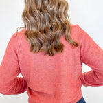 Person wearing a pink sweater and blue jeans against a white background