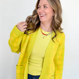 Woman wearing a yellow jacket and shirt against a white background