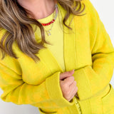 Person wearing a bright yellow sweater against a white background