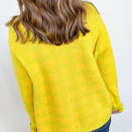 Person wearing a yellow sweater against a white wall