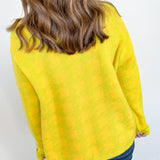 Person wearing a yellow sweater against a white wall