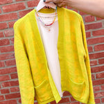 Yellow cardigan on a hanger against a red brick wall