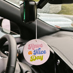Car air freshener with 'Have a Nice Day' message hanging from a car's rearview mirror.