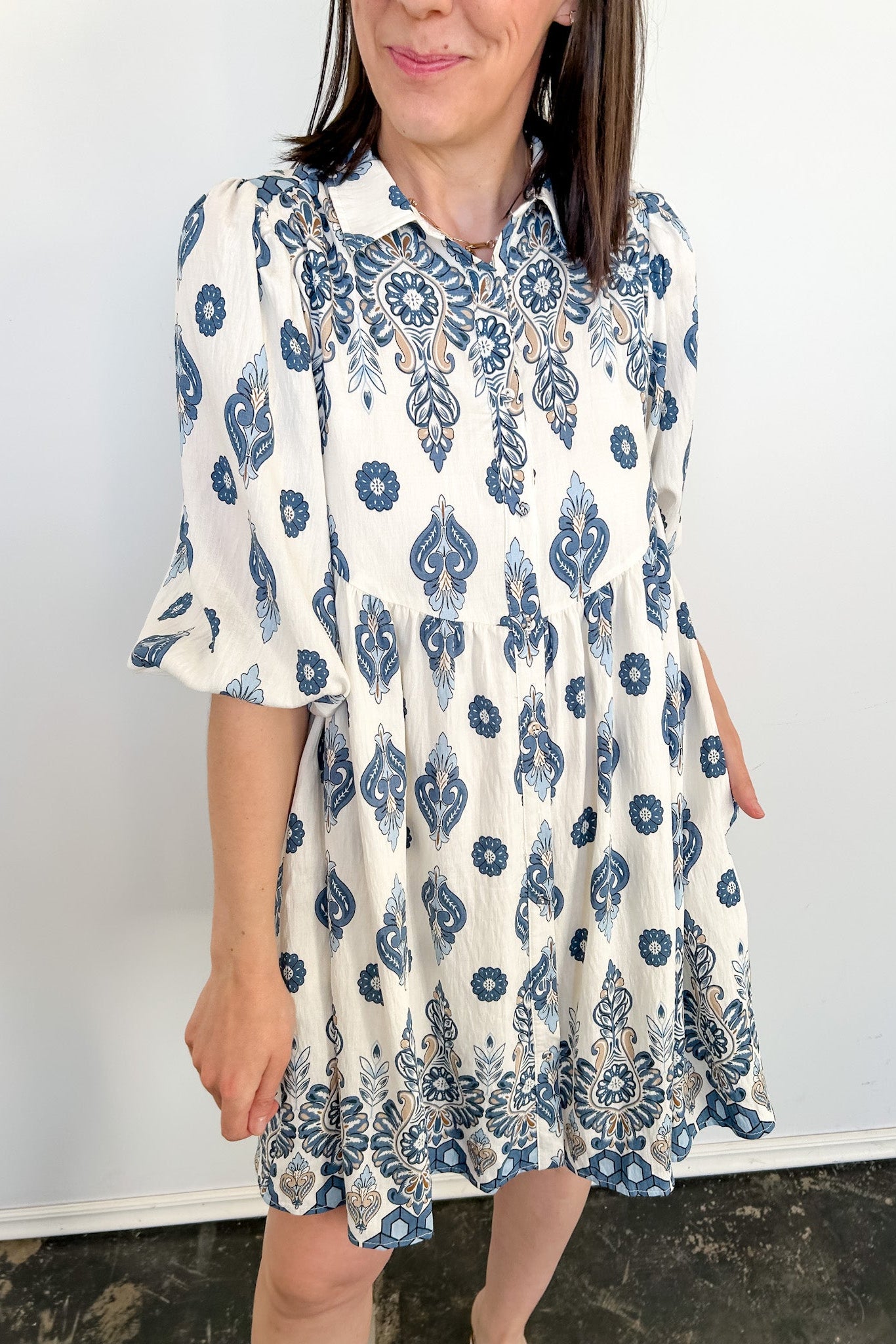 Woman wearing a blue and white patterned dress against a plain background