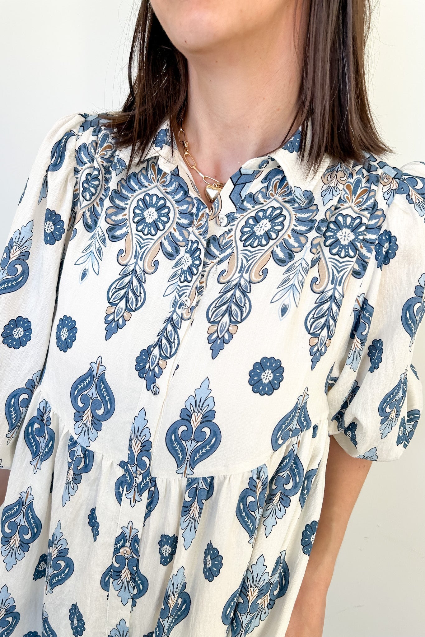 Woman wearing a blue and white patterned blouse against a neutral background