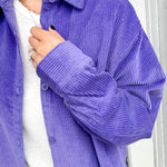 Person wearing a purple corduroy shirt with a white background