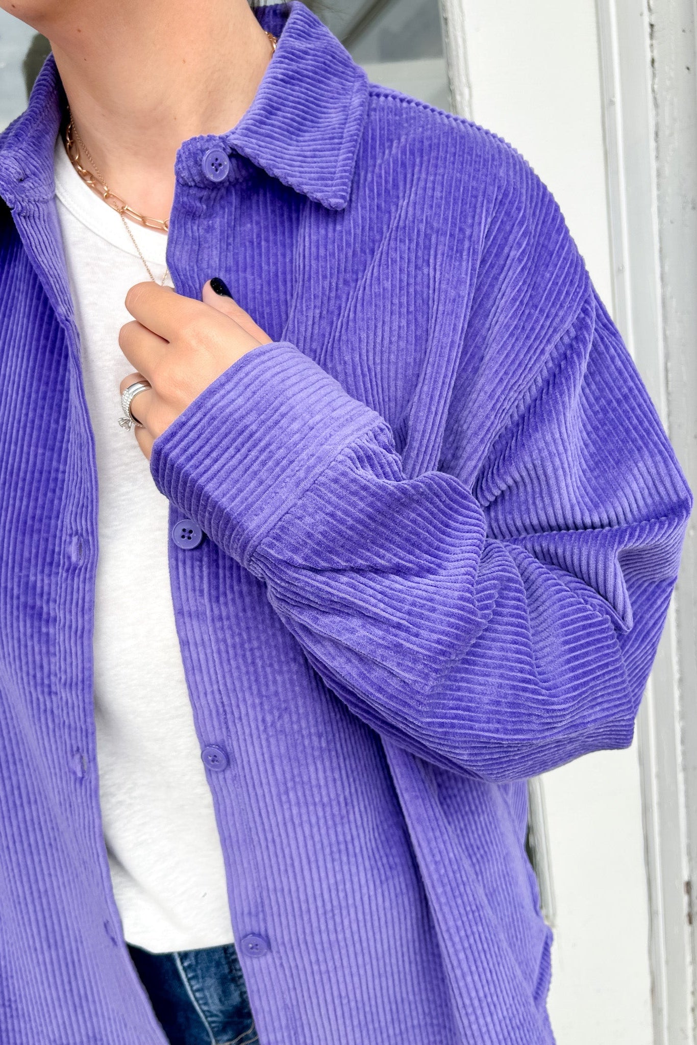 Person wearing a purple corduroy shirt with a white background