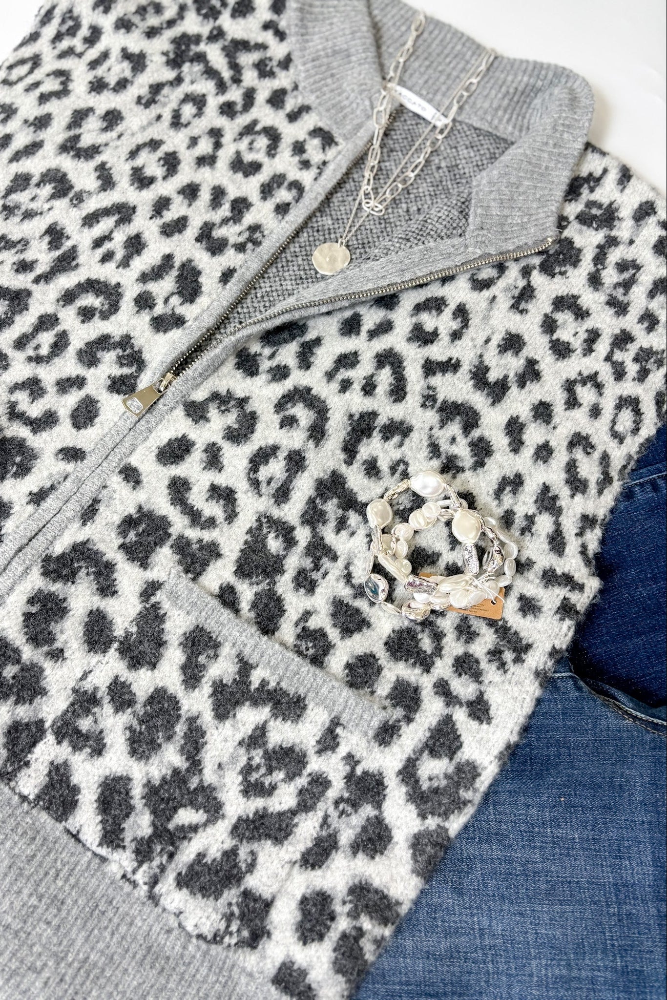 Leopard print vest with gray collar and trim, paired with jeans and a necklace.