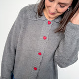 Woman wearing a gray sweater with red buttons on a white background