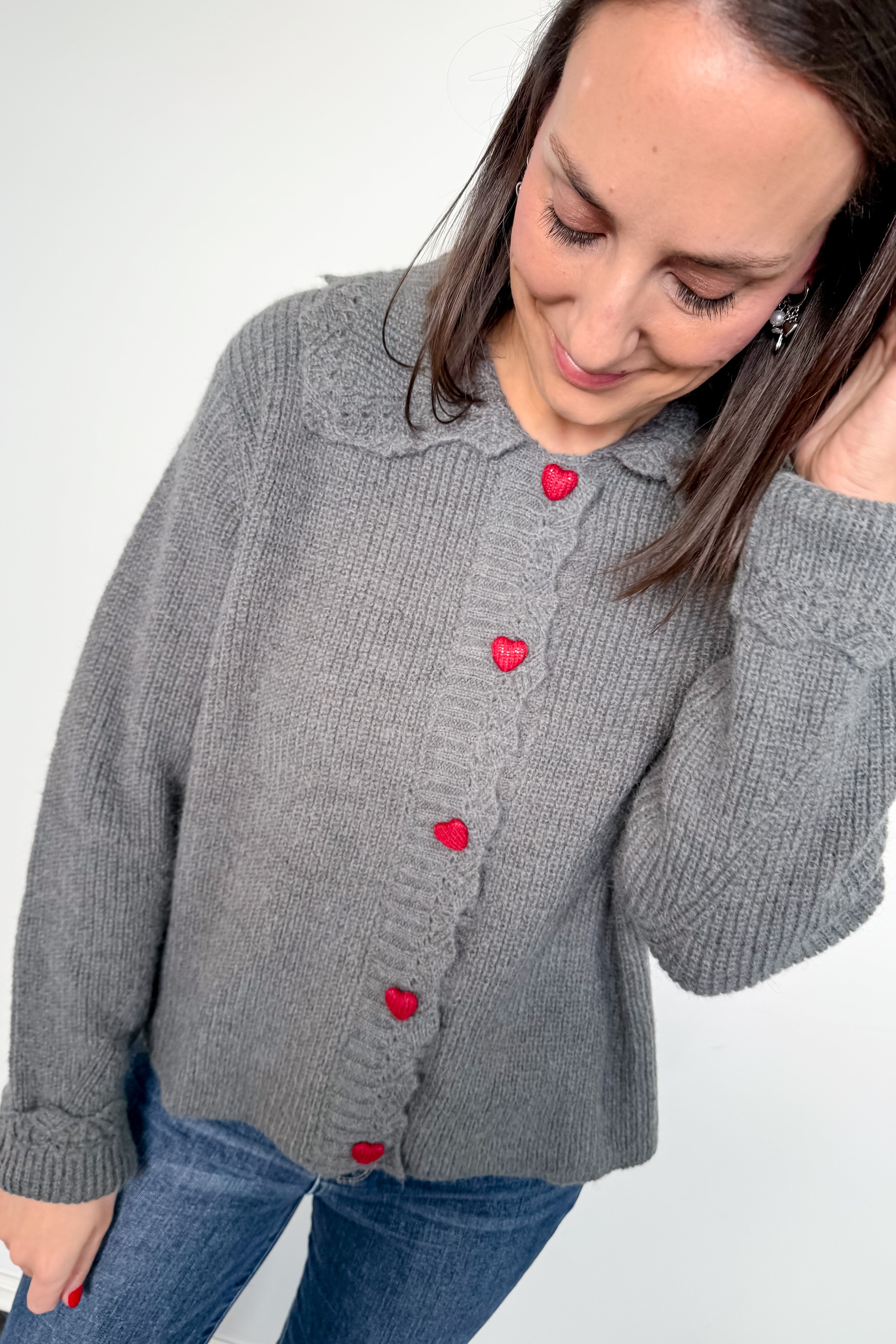 Woman wearing a gray sweater with red buttons on a white background