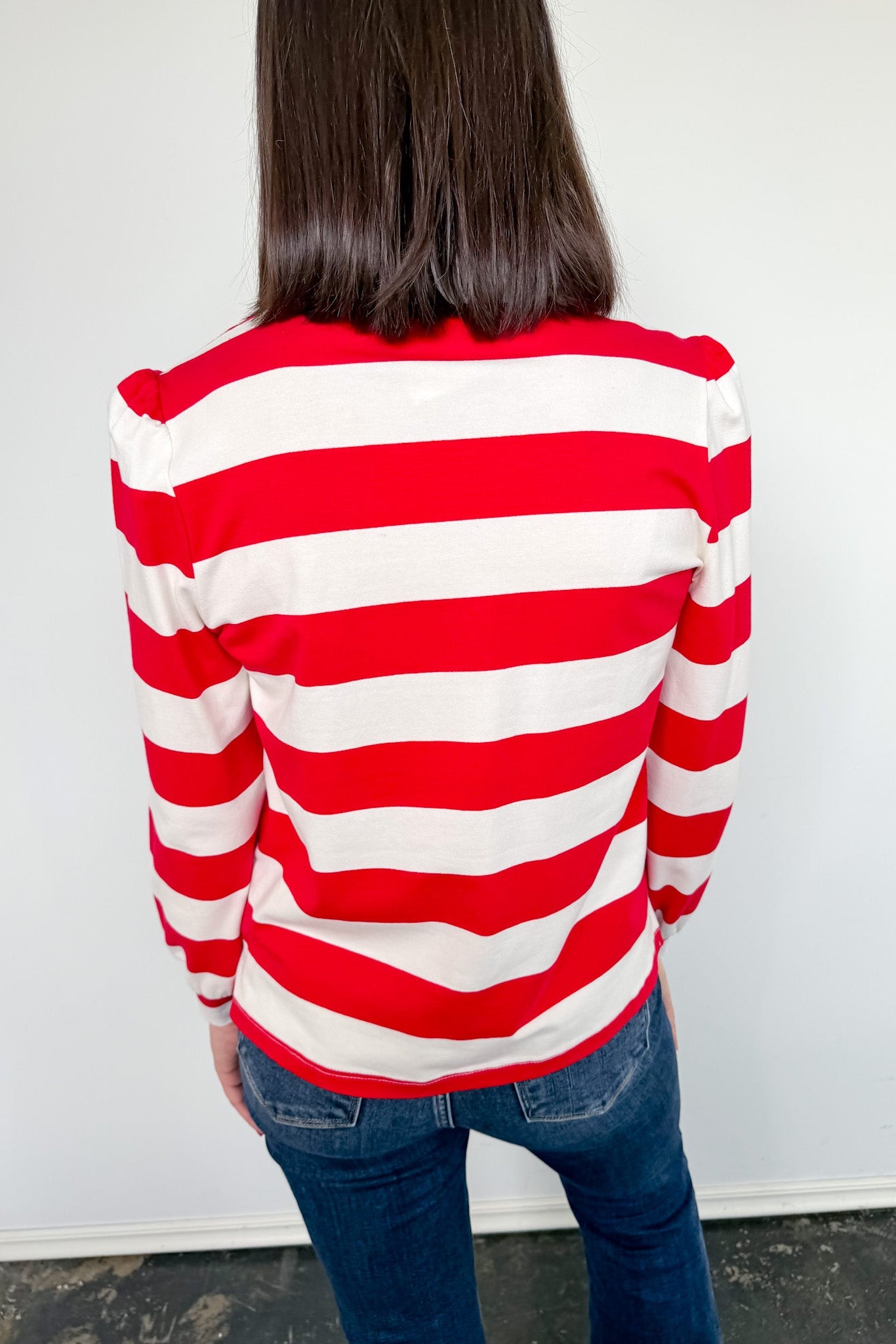 Person wearing a red and white striped sweater against a plain background