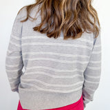 Person wearing a gray striped sweater and red pants against a white background