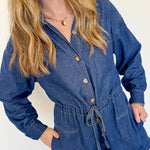 Woman wearing a blue denim romper against a white background