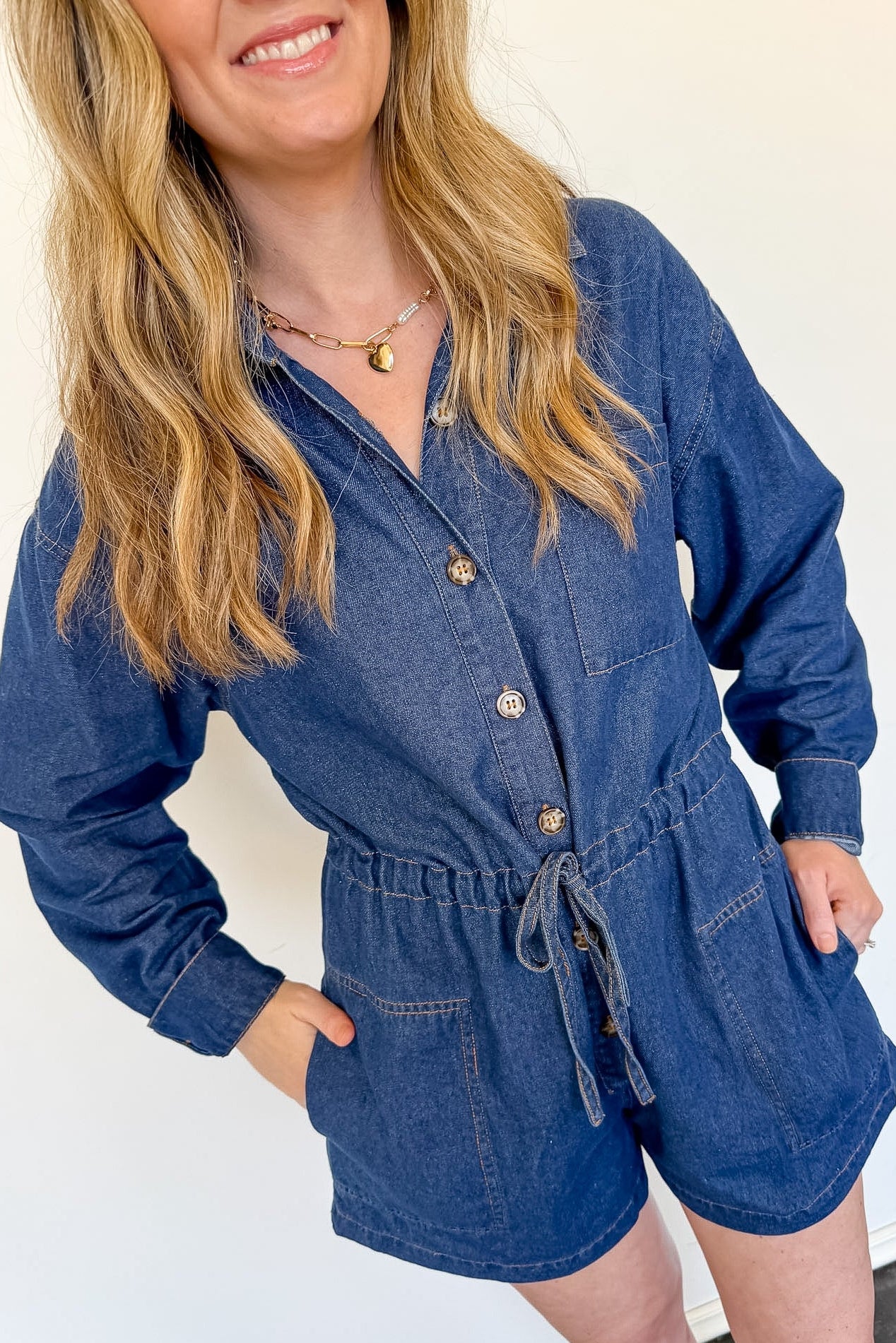 Woman wearing a blue denim romper against a white background