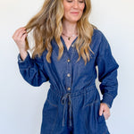 Woman wearing a blue denim romper against a plain background