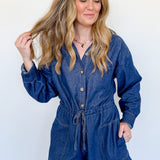 Woman wearing a blue denim romper against a plain background