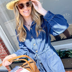 Woman in a denim romper and straw hat holding a basket with a checkered bag.