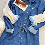 Blue denim dress with beige sleeves on a neutral background