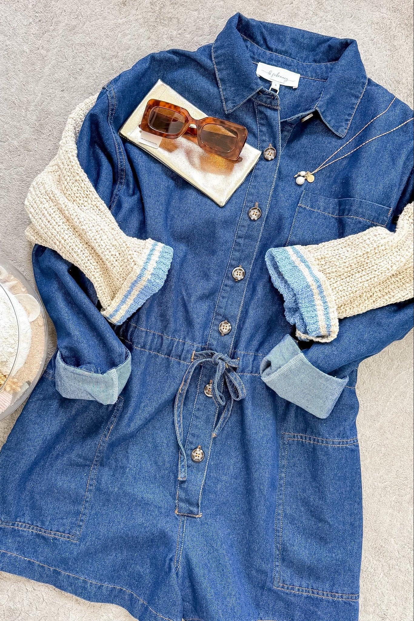 Blue denim dress with beige sleeves on a neutral background