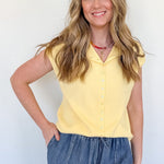 Woman wearing a yellow top and blue jeans against a white background