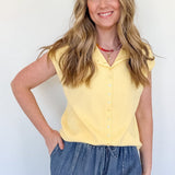Woman wearing a yellow top and blue jeans against a white background