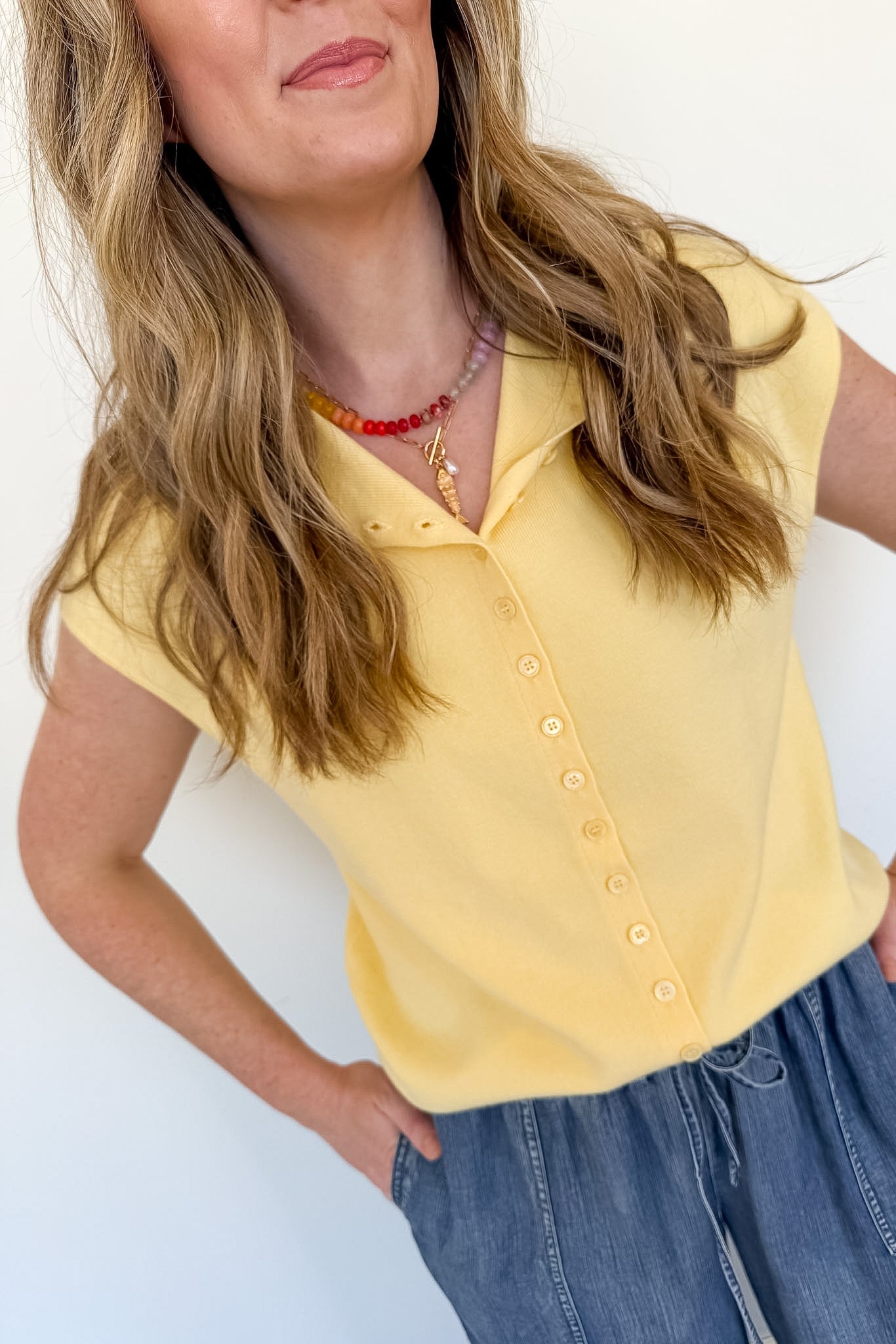 Woman wearing a yellow blouse and blue jeans against a white background