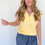 Woman wearing a yellow top and blue jeans against a white background