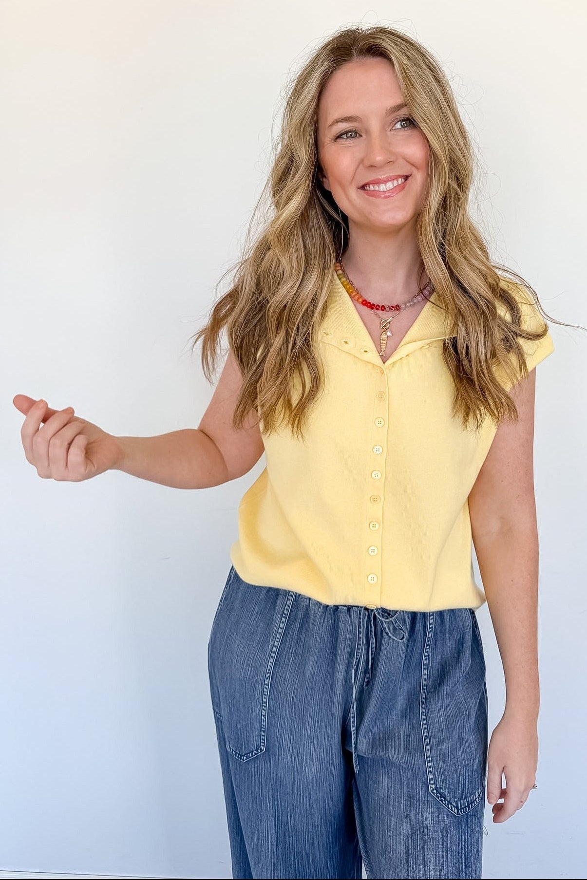 Woman wearing a yellow top and blue jeans against a white background
