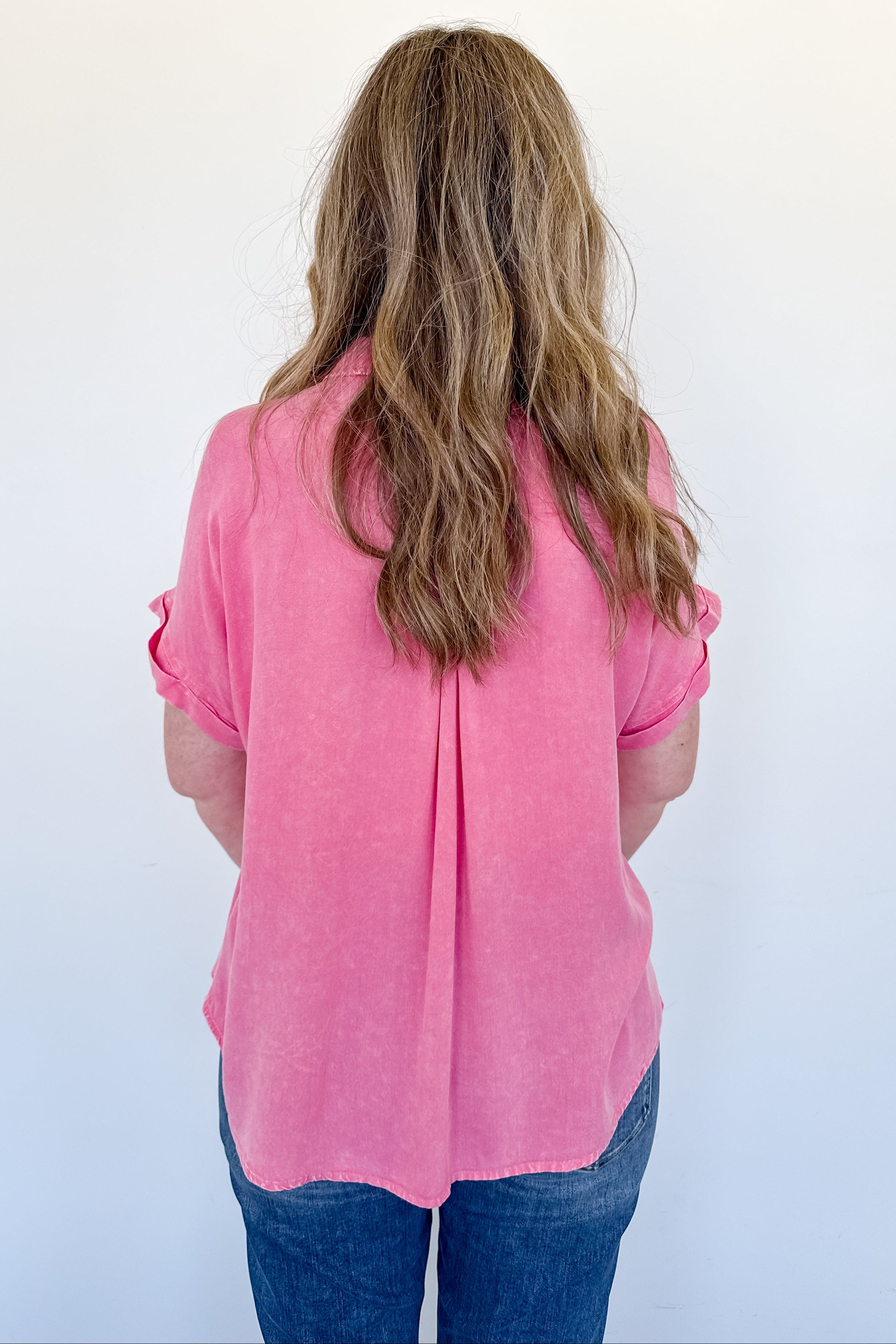 Person wearing a pink shirt from behind on a white background