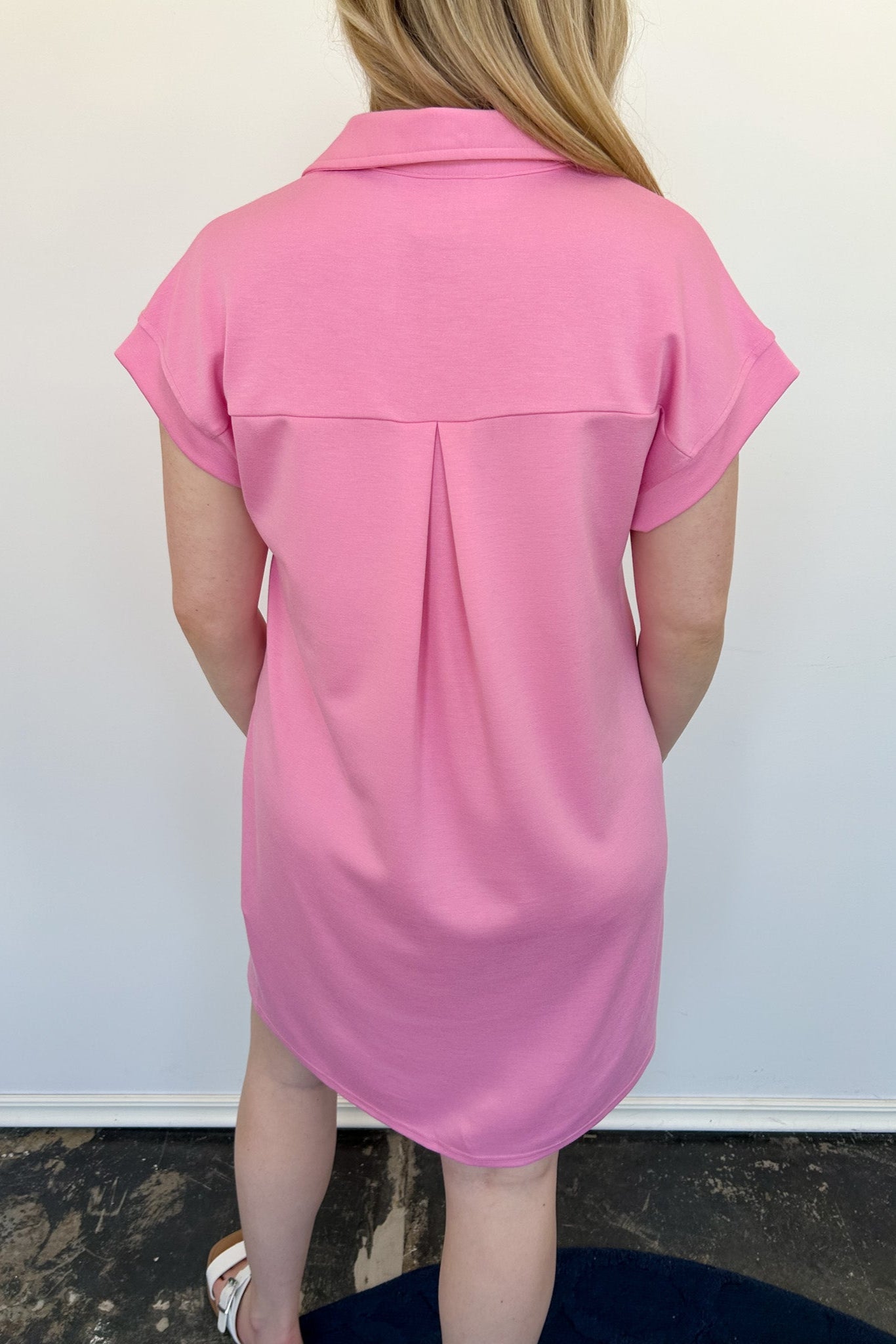 Athleisure dress that hits above the knees. Collared and short sleeve. Features a v neckline and pockets. Pink in color.