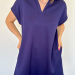 Athleisure dress that hits above the knees. Collared and short sleeve. Features a v neckline and pockets.  Navy in color.