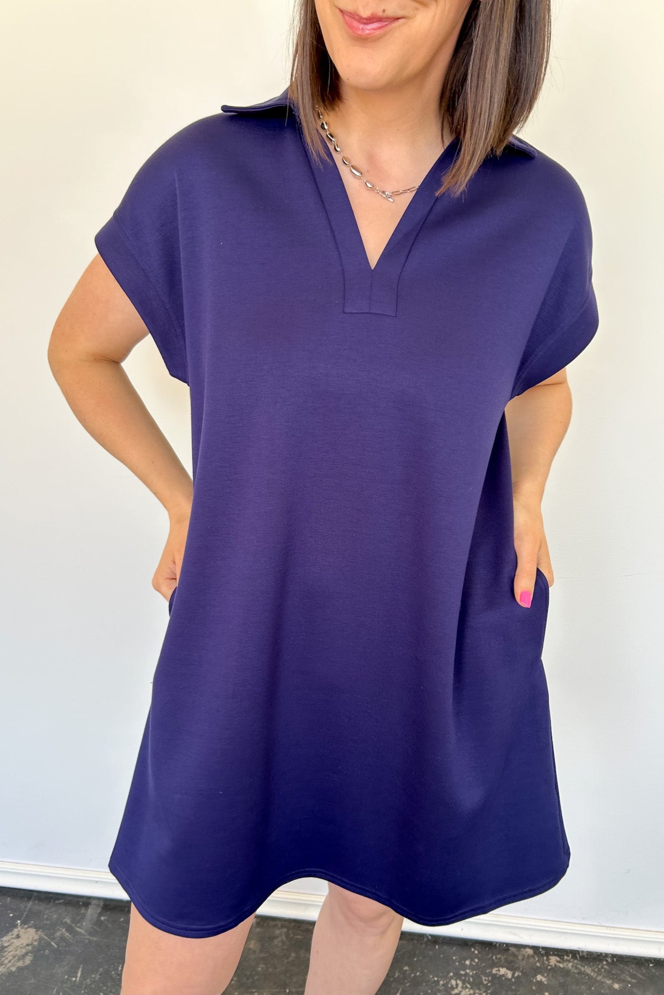 Athleisure dress that hits above the knees. Collared and short sleeve. Features a v neckline and pockets.  Navy in color.