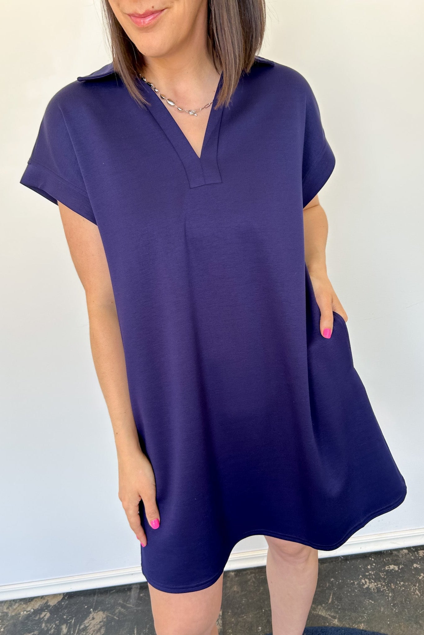 Athleisure dress that hits above the knees. Collared and short sleeve. Features a v neckline and pockets.  Navy in color.
